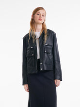 A blonde woman wears a black leather jacket.